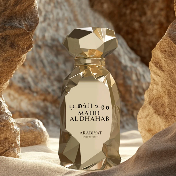 Gold perfume bottle labeled 'MAHD AL DHAHAB' by Arabiyat Prestige against a desert rock background